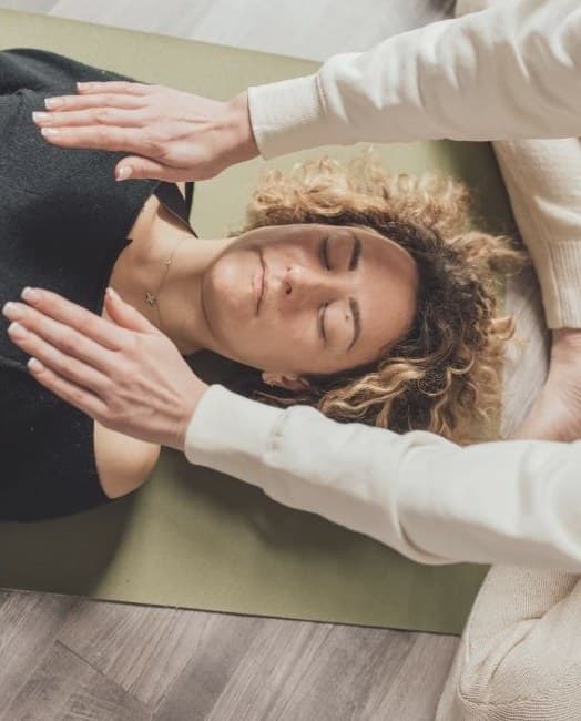 Zabieg Reiki — dłonie nad osobą leżącą w stanie głębokiego relaksu